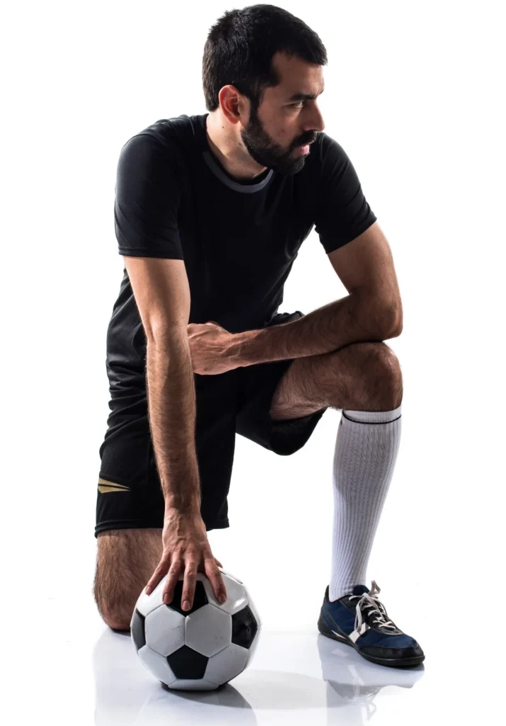 Deportista sentado sujetándose la rodilla, ejemplo de lesión deportiva